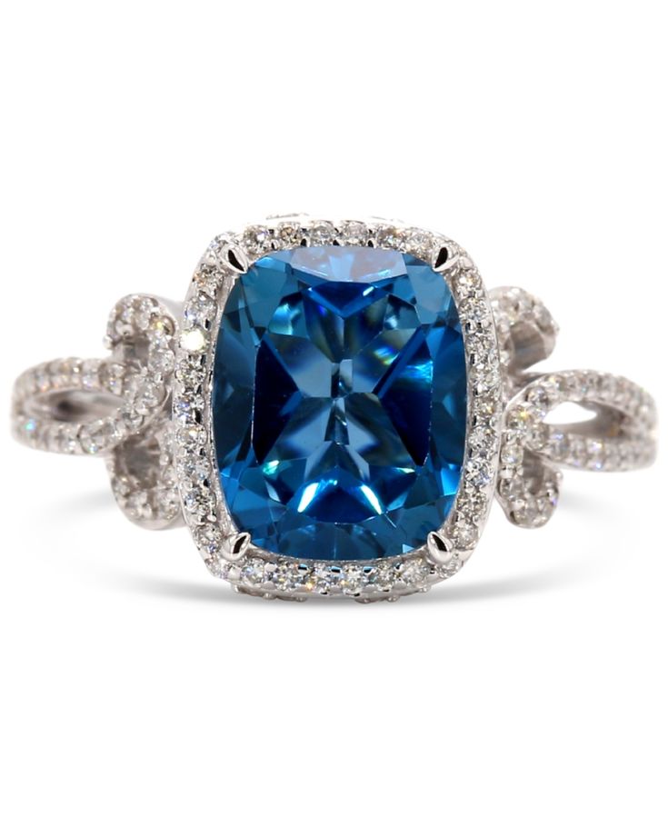 a blue cushion cut diamond ring with two rows of diamonds around the band and an intricate halo