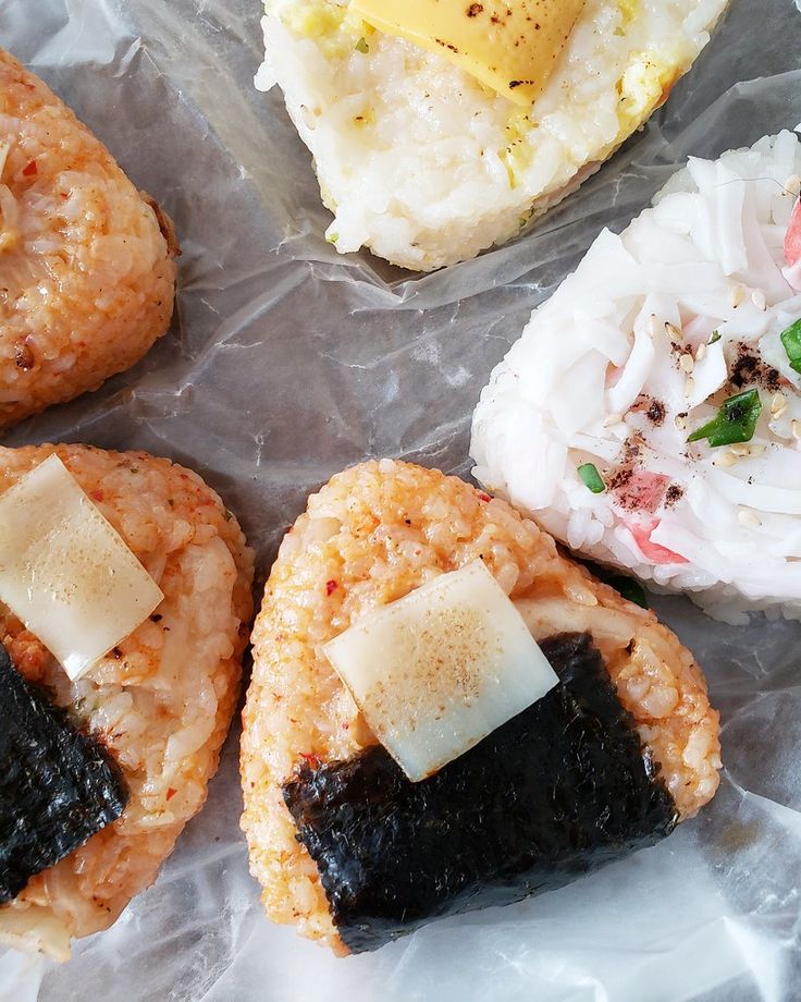 four pastries with different toppings on them sitting on wax paper and wrapped in plastic