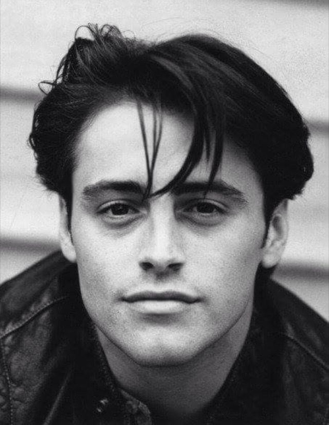 a black and white photo of a man with long hair wearing a leather jacket looking at the camera