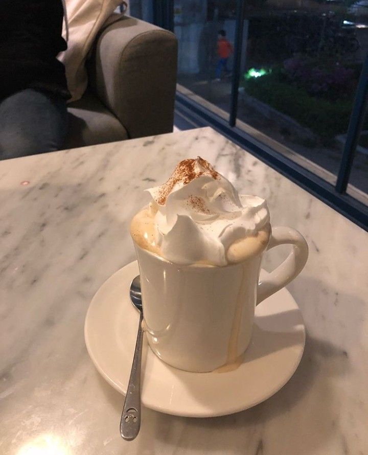 a white cup filled with whipped cream on top of a table