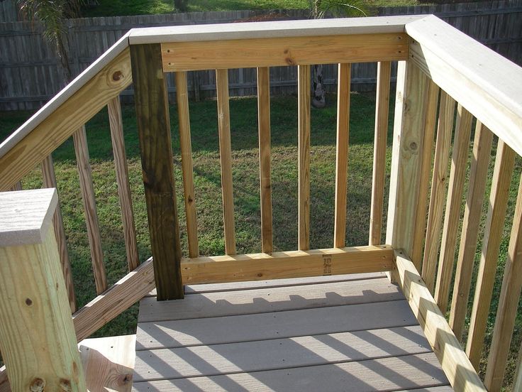 a dog is sitting on the porch next to some stairs and railings that are made out of wood