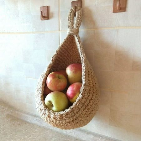 there is a basket with apples in it hanging on the wall next to two hooks