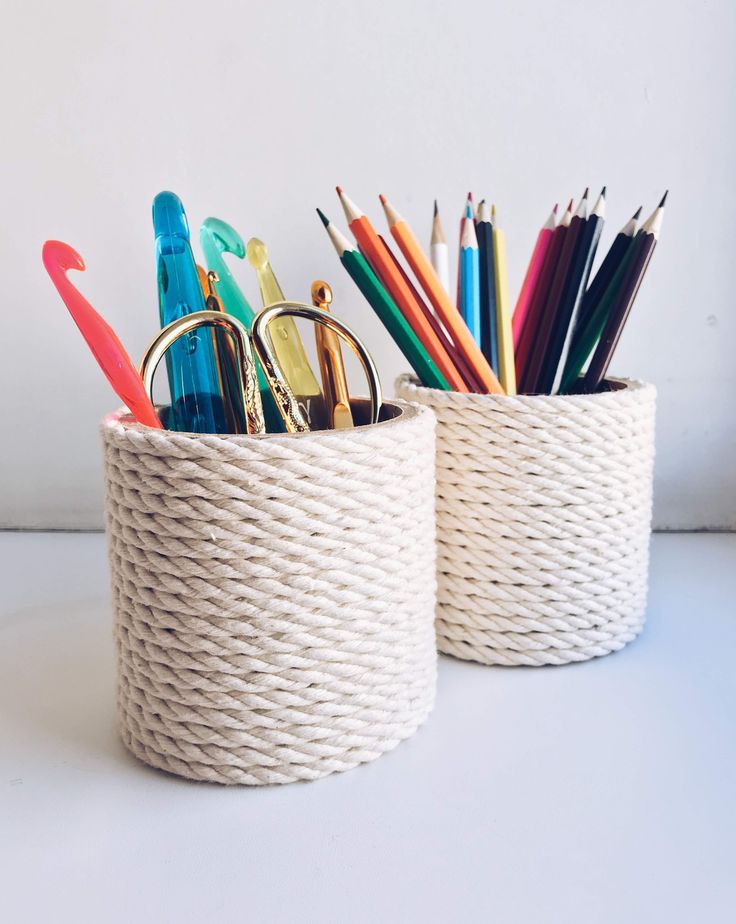 two white baskets filled with pens, pencils and scissors