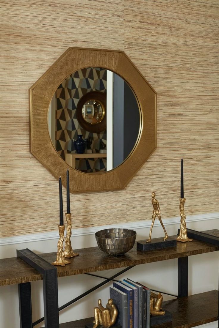 a table with some books and a mirror on it next to a book shelf in front of a wall