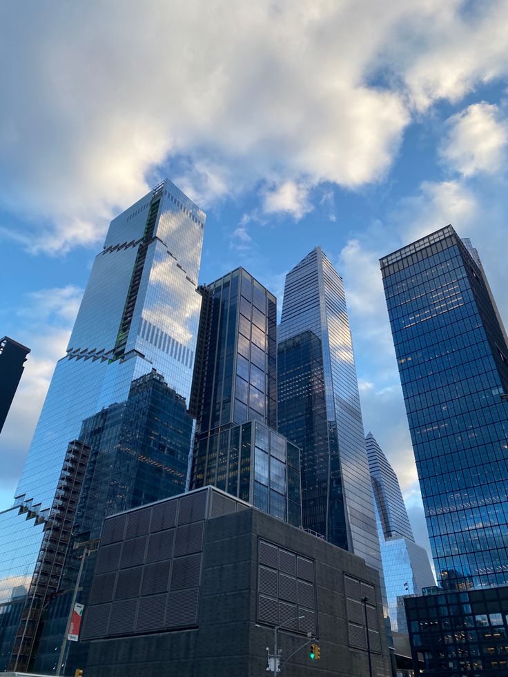 there are many tall buildings in the city with blue sky and white clouds above them