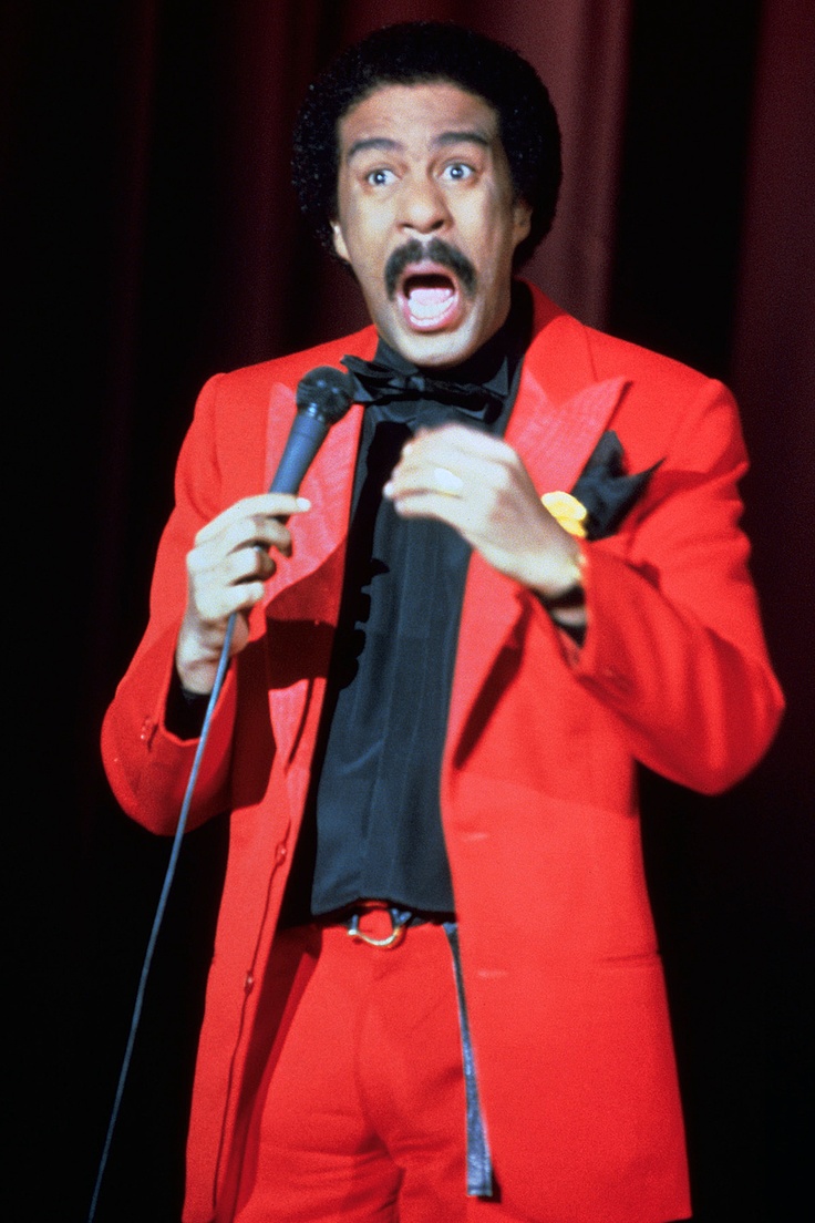 a man in a red suit singing into a microphone