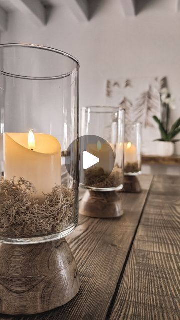 a wooden table topped with glass vases filled with candles