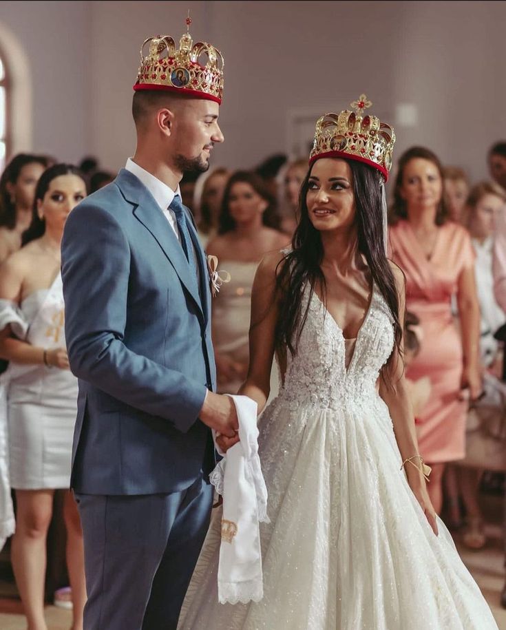 a man in a suit and tie standing next to a woman wearing a tiara