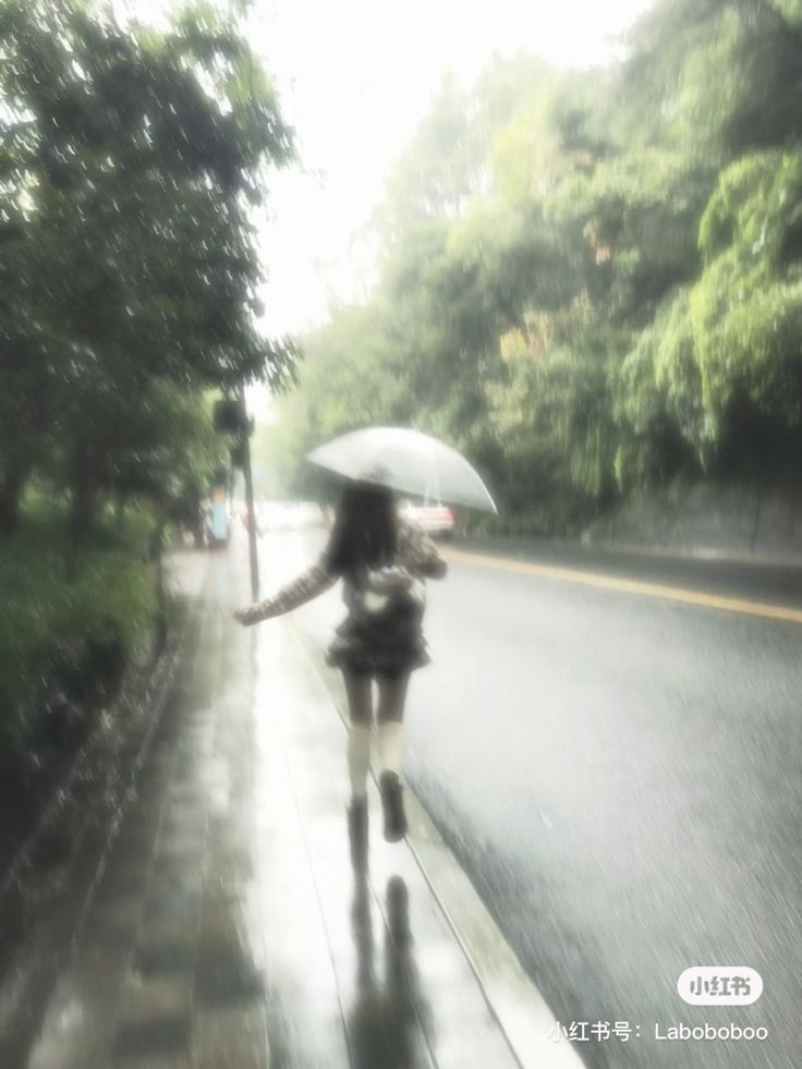 a woman walking down the street in the rain with an umbrella