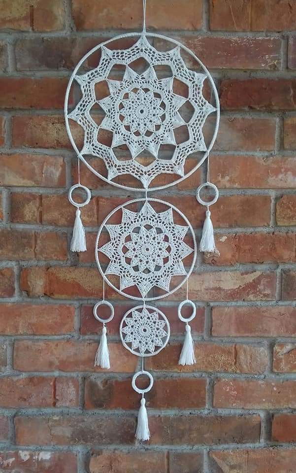 a white metal wind chime hanging on a brick wall