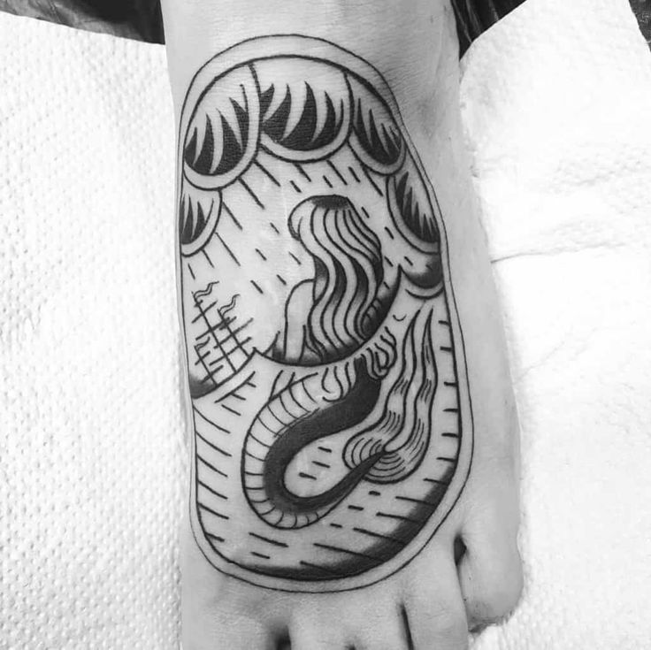 a black and white photo of a person's foot with a tattoo on it