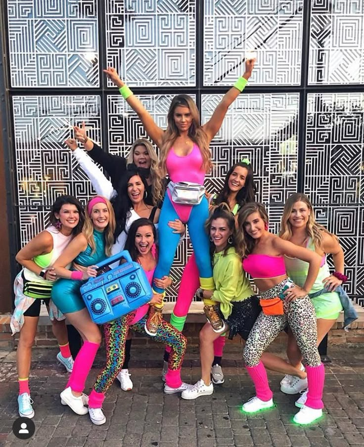 a group of women posing in front of a building with their arms up and legs crossed