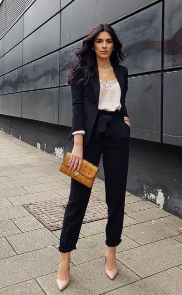 a woman is standing on the sidewalk with her hand in her pocket and holding a purse