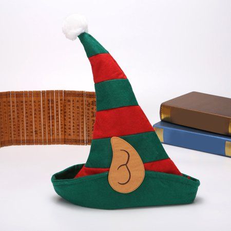 a green and red elf hat sitting on top of a table next to two books