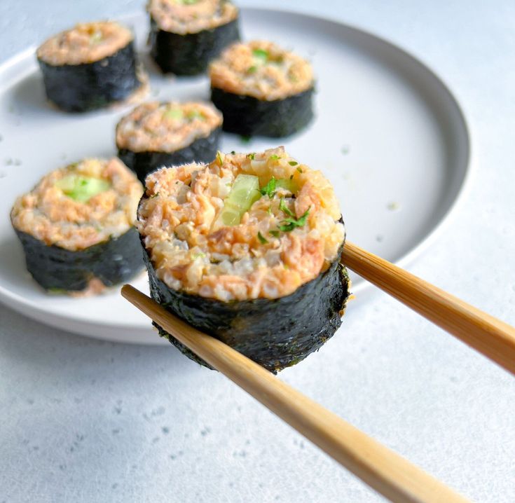 sushi on a white plate with chopsticks