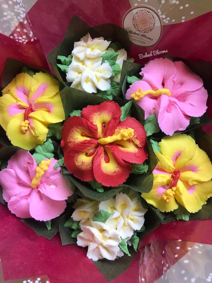 a bunch of flowers that are sitting in a vase on a table with red and yellow ribbons