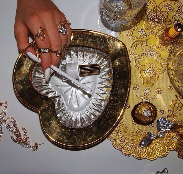 a person holding a knife and fork in front of a plate with jewelry on it