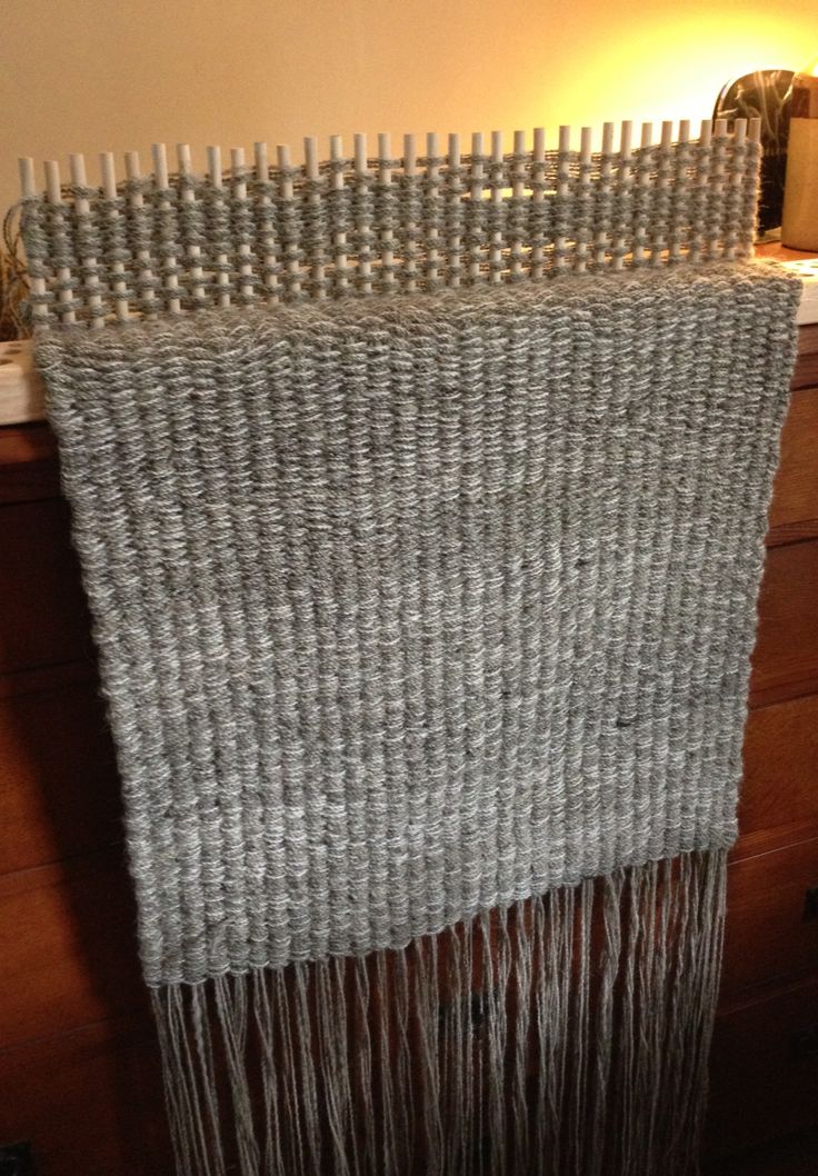 a close up of a weaving machine on a wooden table next to a wall lamp