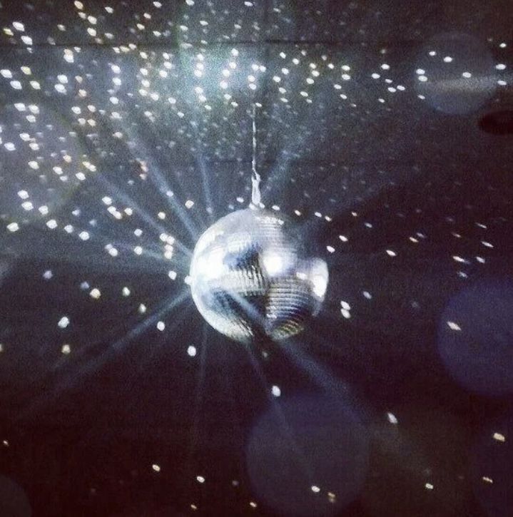 a disco ball hanging from the ceiling in front of some bright lights and sparkles