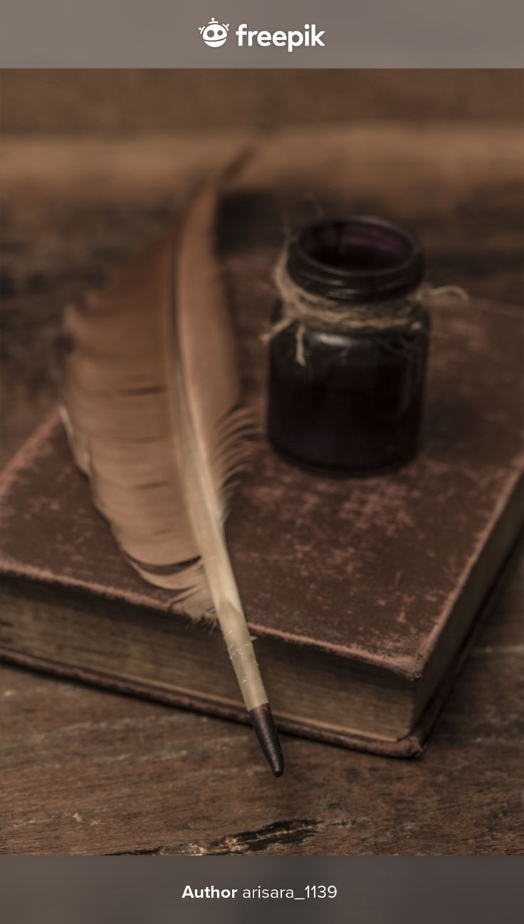 an old book with a feather quill and ink pen sitting on top of it