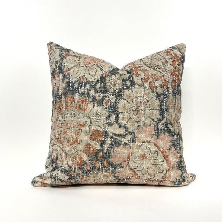 an orange and blue floral pillow on a white background