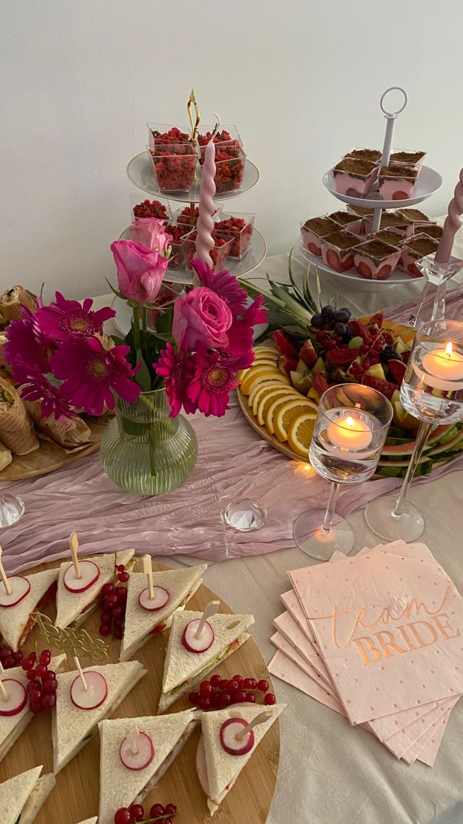 a table topped with lots of desserts and candles next to plates filled with food