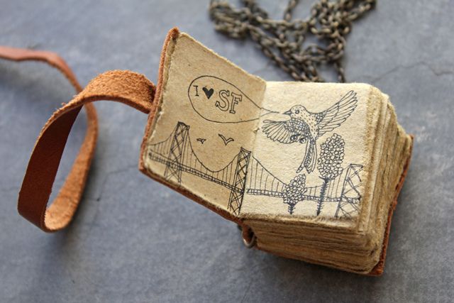 an old book with a bird on it is sitting on a table next to a chain