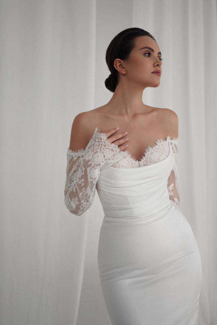 a woman in a white dress is posing with her hands on her chest and arms behind her back