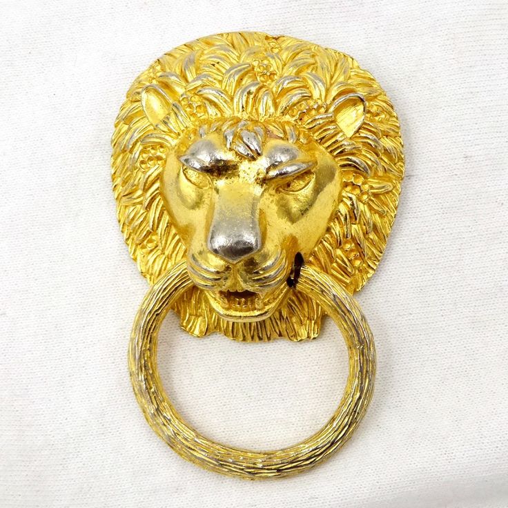 a gold lion head door knocker on a white background with a ring in the foreground