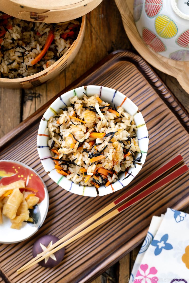 there is a bowl of rice and two bowls of food on the table with chopsticks