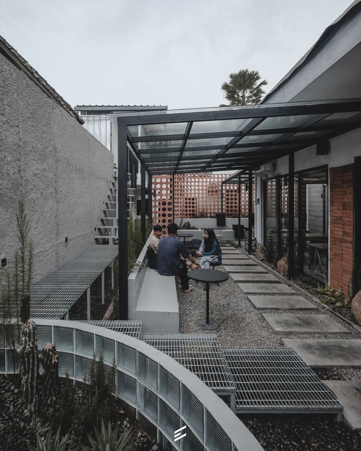 people sitting on benches in an outdoor area with pergolated walls and metal railings