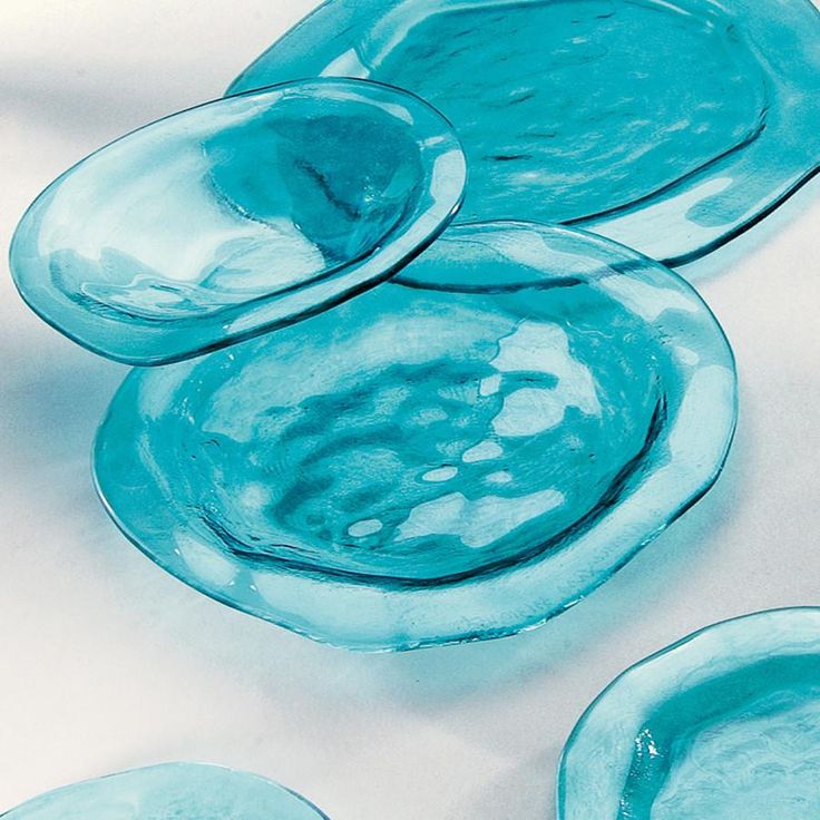 three blue glass plates sitting on top of a white table