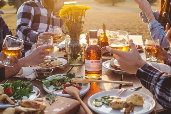 people sitting at a table with food and drinks in front of them, all holding utensils