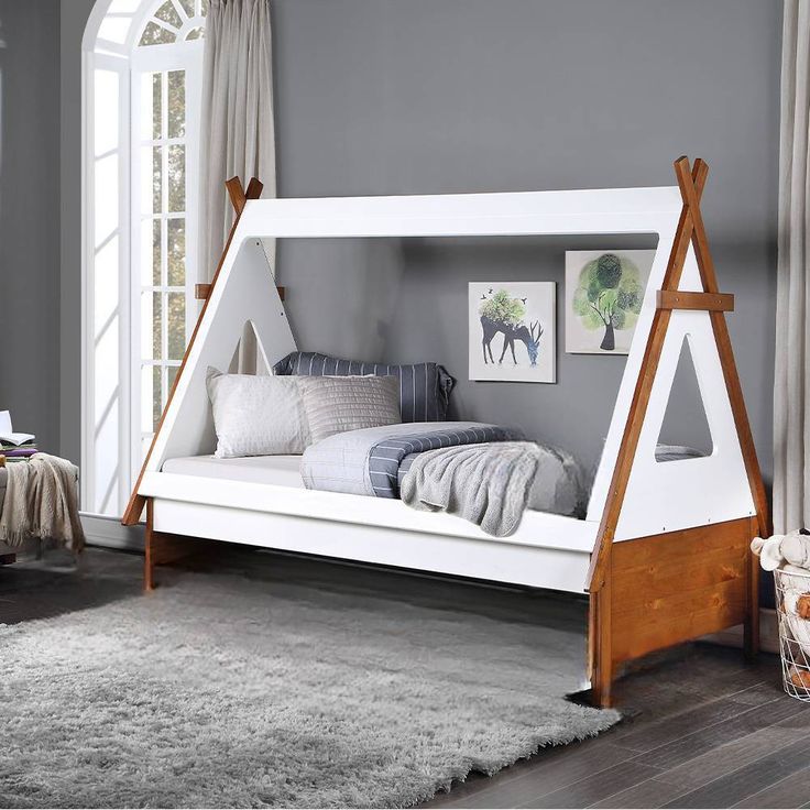 a child's bed with a teepee shaped frame and wooden legs in a bedroom