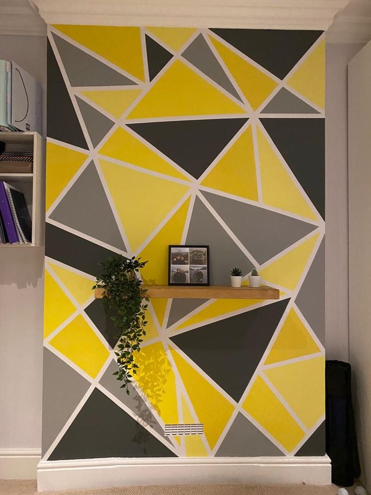 a yellow and grey geometric wallpaper in a living room with bookshelves on the shelves