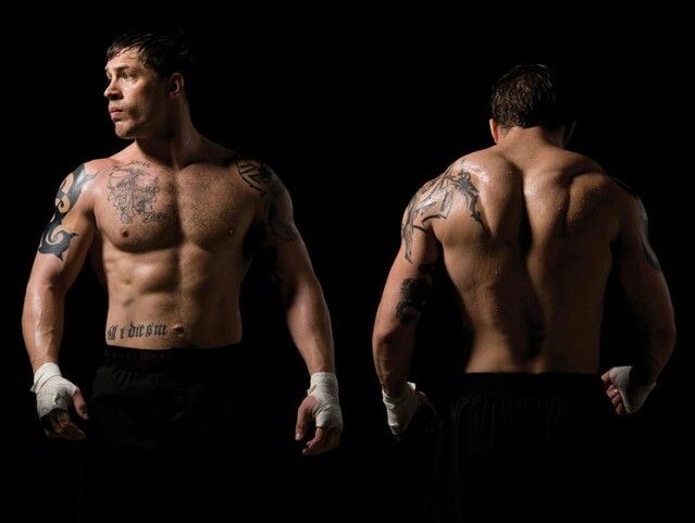 two men with tattoos on their arms and chest standing in front of a black background