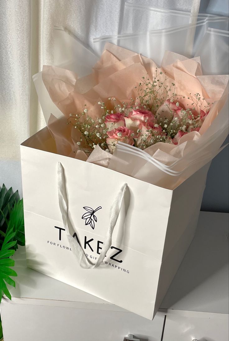 a white paper bag with flowers in it