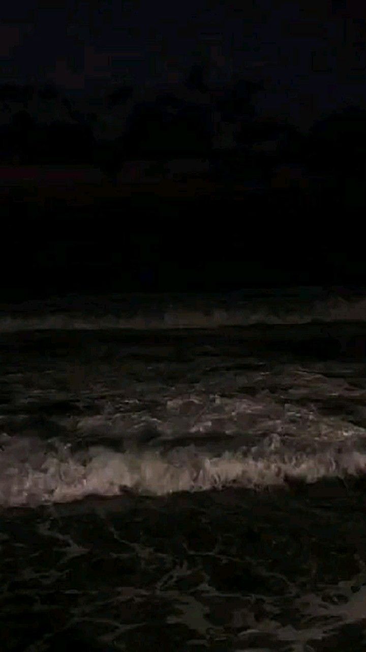 a person standing in the ocean at night