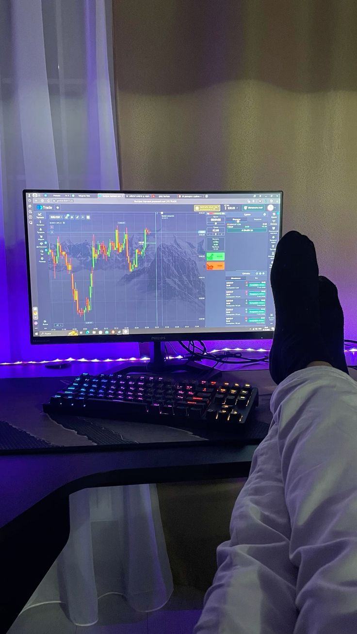 a man sitting in front of a computer monitor with a stock chart on the screen