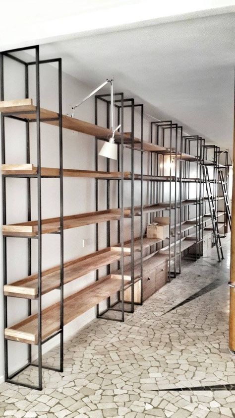 an empty room with shelves and ladders in the corner, next to a brick floor