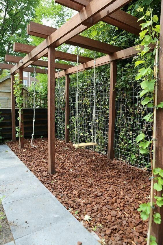 an outdoor garden with lots of leaves and plants growing on the fenced in area