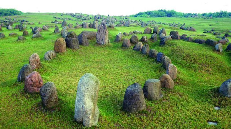 an aerial view of several large rocks in the grass