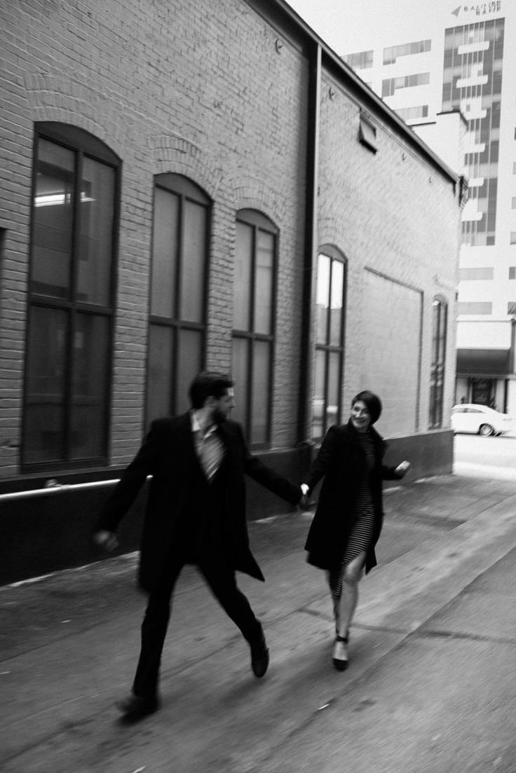 black and white photograph of two people walking down the street with their hands in each other's pockets