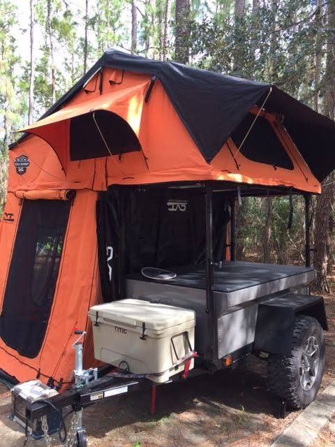 an orange and black tent is in the woods with its canopy opened to provide shade