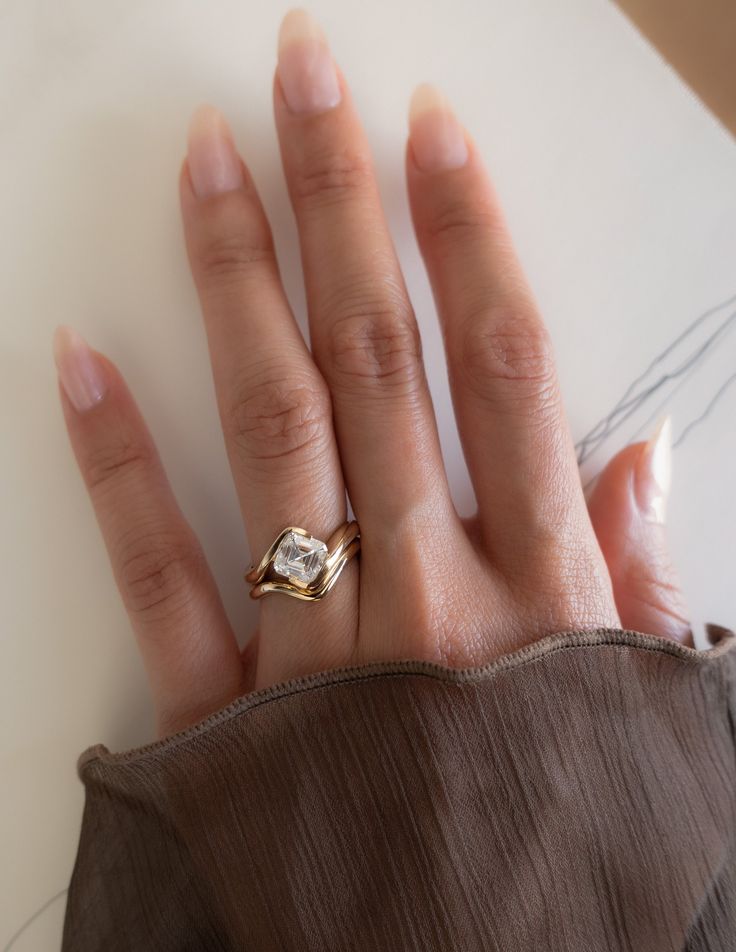 a woman's hand with a gold ring on top of her left hand, and a diamond in the middle