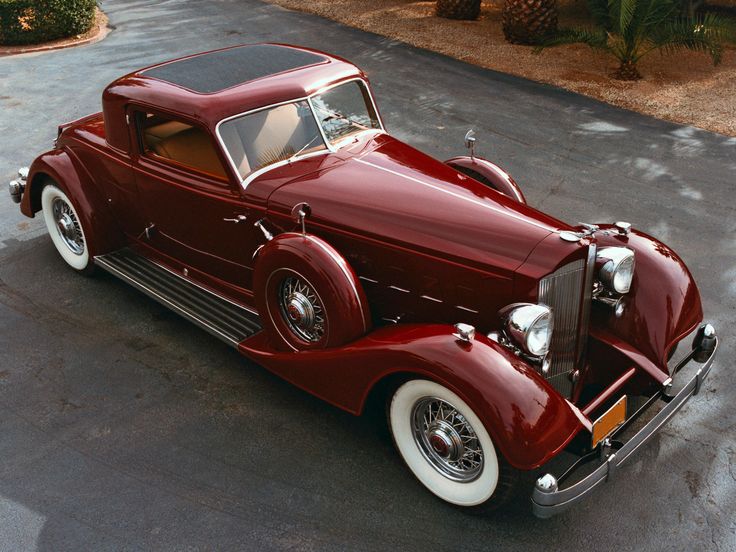 an antique red car parked in a parking lot