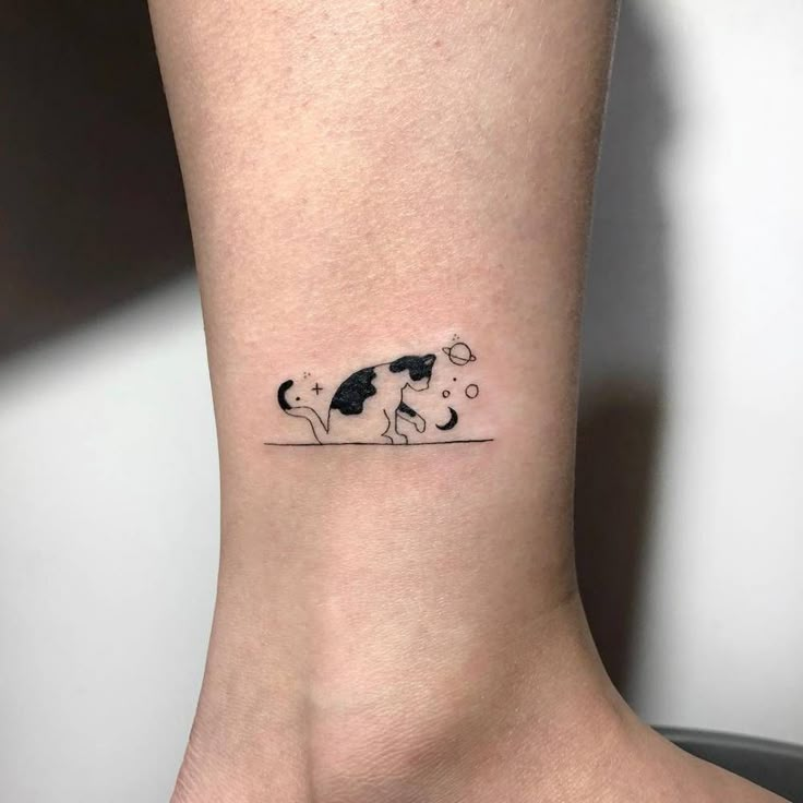 a small black and white dog tattoo on the ankle