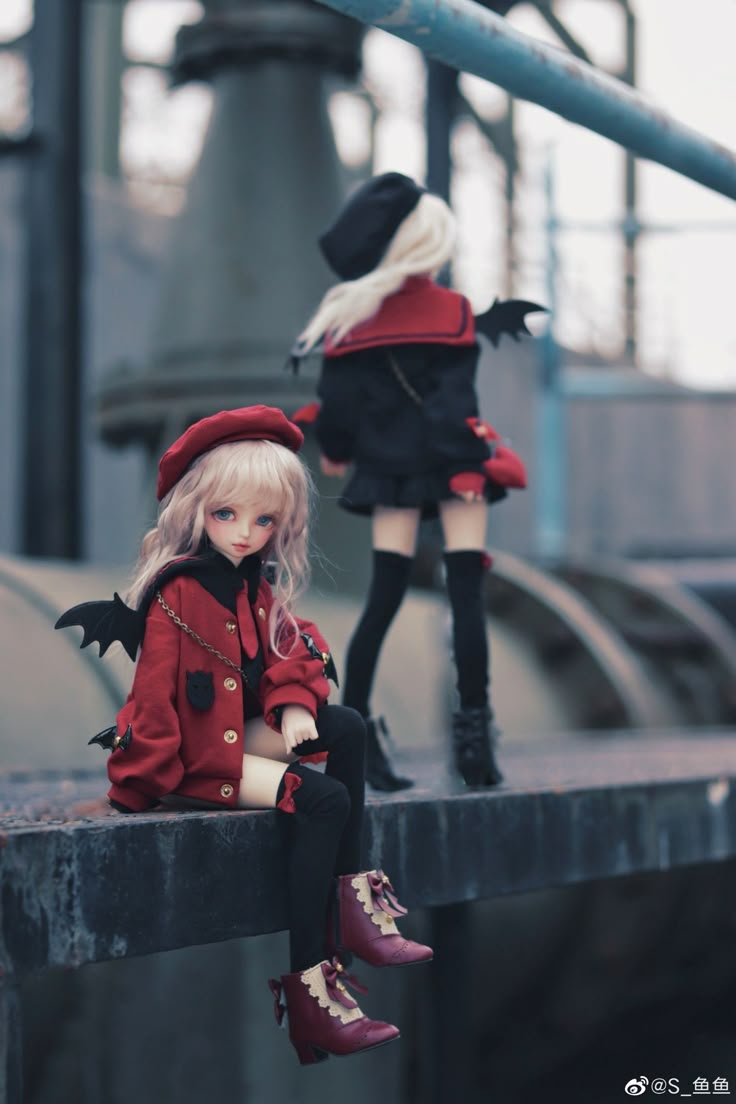 two dolls dressed in red and black are sitting on a ledge next to each other