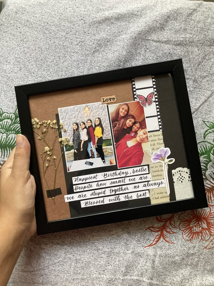 a person holding up a frame with pictures and words in it on top of a bed