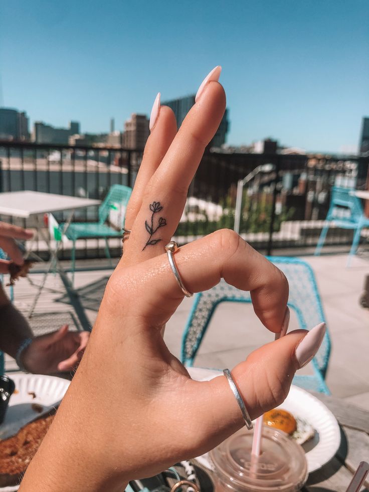 a woman's hand with a small tattoo on her left thumb and the word love written in it